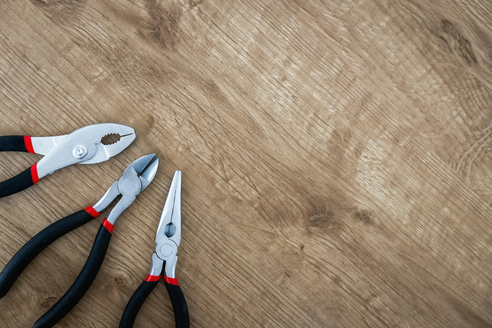 Three pairs of pliers on a wooden surface